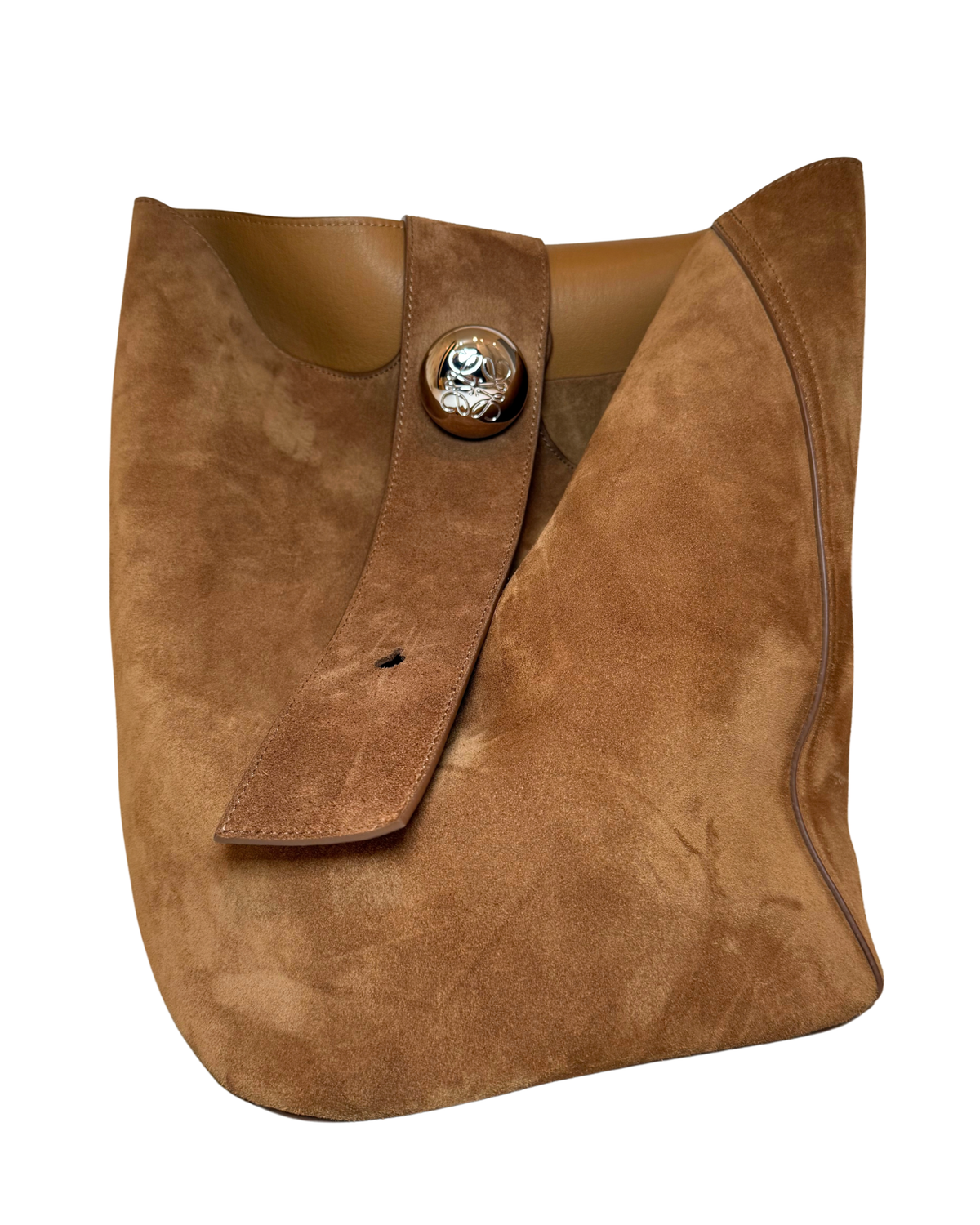 A brown suede shoulder bag with a wide strap and a decorative round metal button closure, shown on a plain white background.