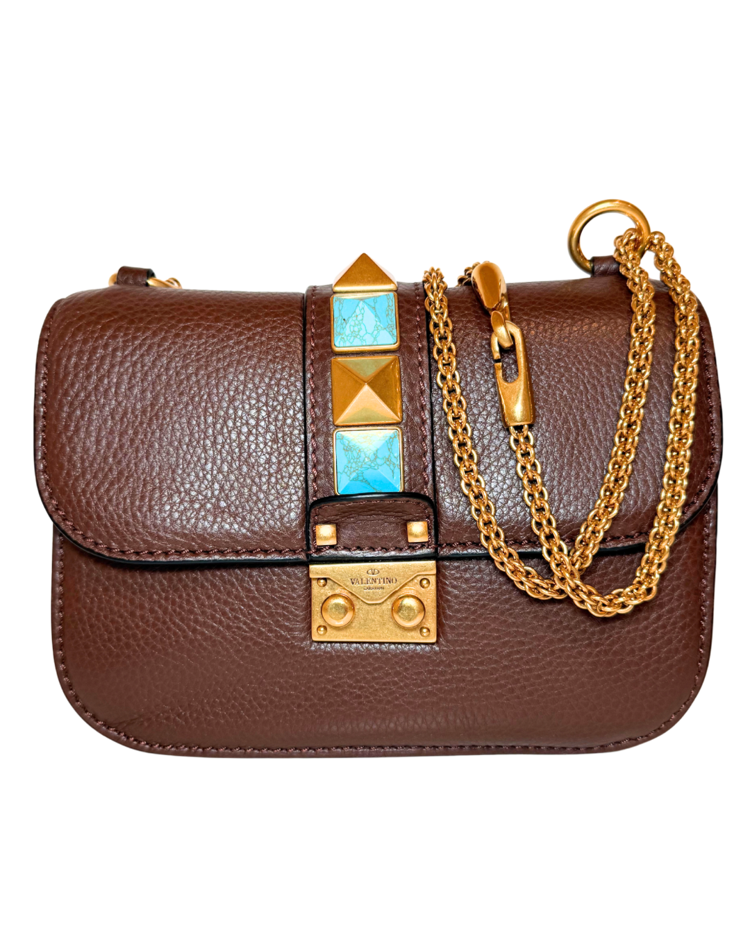 A brown pebbled leather shoulder bag with gold-tone hardware, featuring a vertical column of pyramid studs and turquoise blue rhinestone accents on the front flap, and a gold chain strap draped over the side.