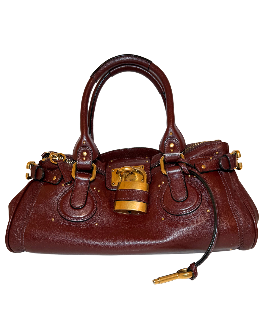 A dark reddish-brown leather handbag with gold-tone hardware, featuring dual top handles, a front flap with studs, shown against a plain white background.