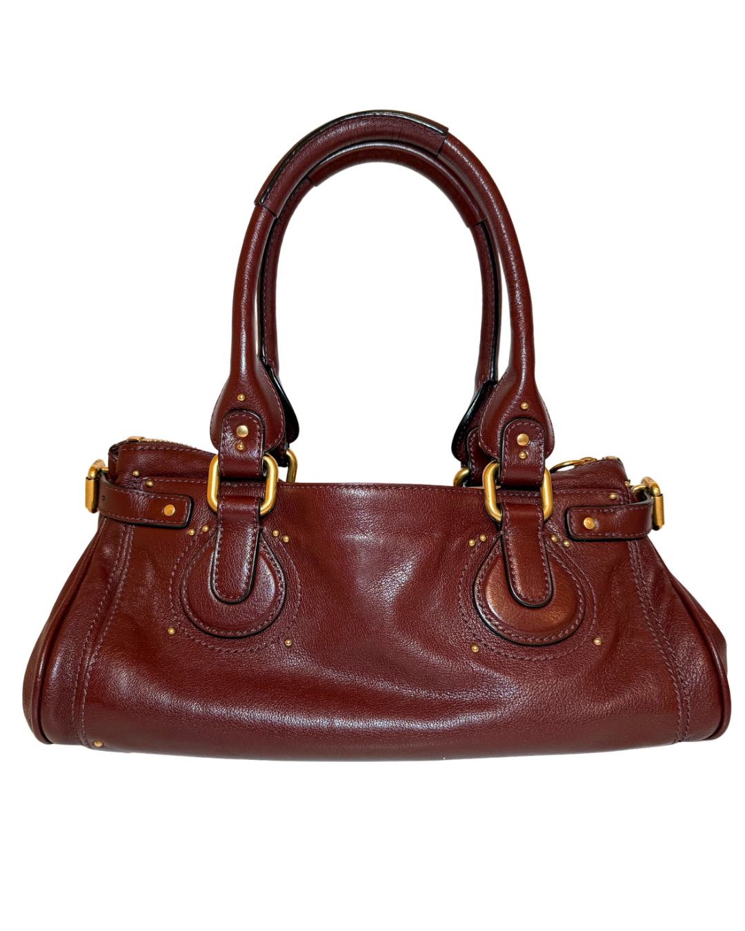 A dark reddish-brown leather handbag with gold-tone hardware, featuring dual top handles, a zip-top closure, and decorative rivets, shown against a plain white background.