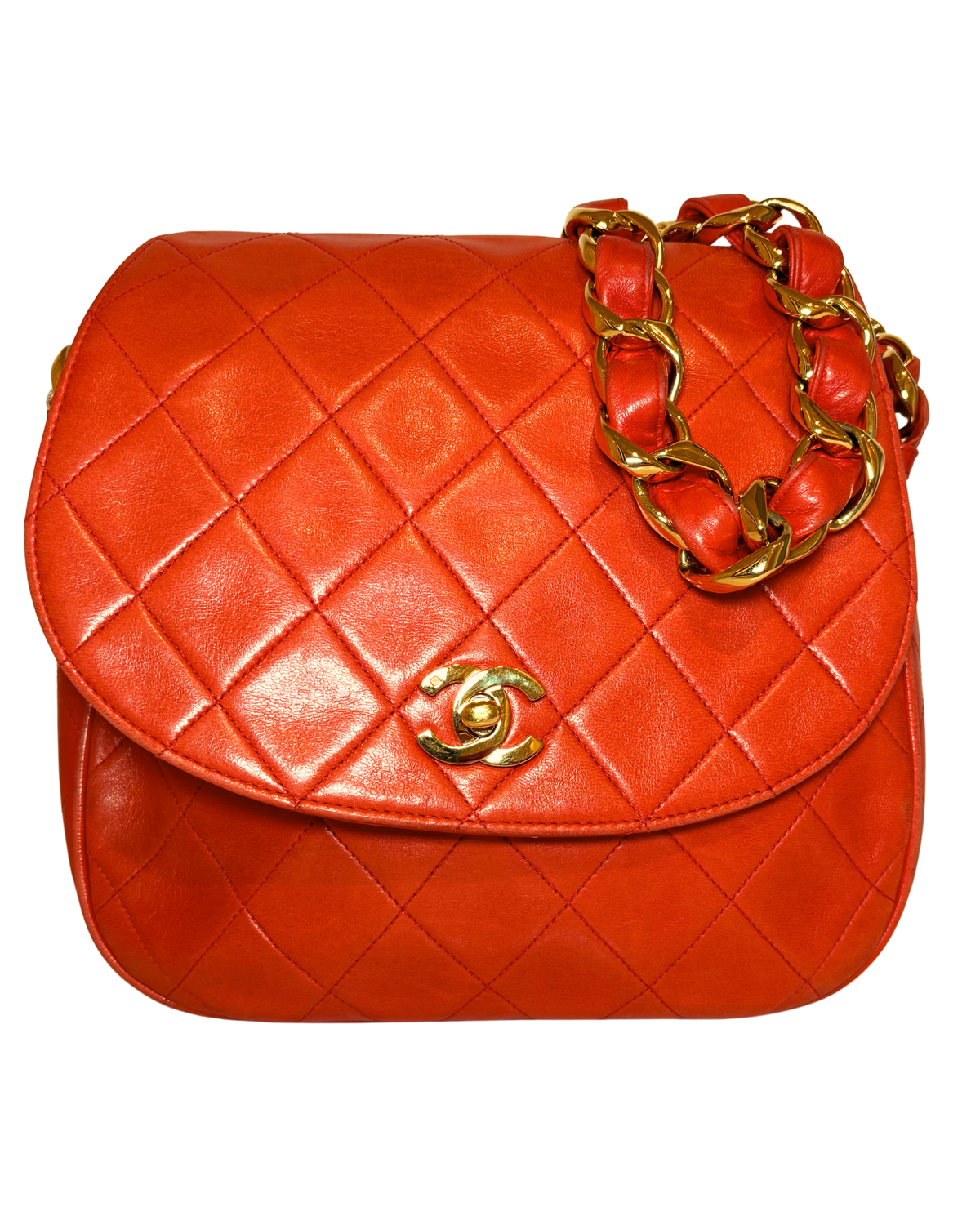 A quilted orange-red leather shoulder bag with a gold-tone interlocking CC logo and a chunky gold chain strap, shown against a plain white background.