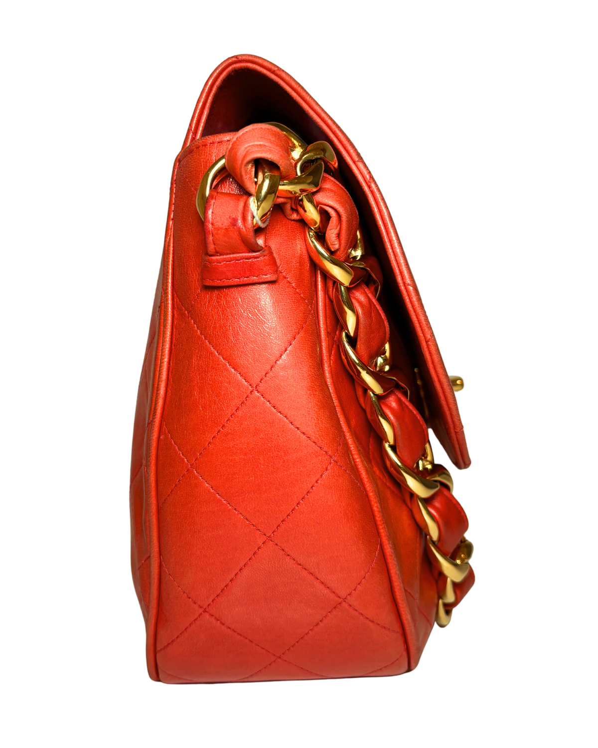 A bright orange-red quilted leather handbag with a gold chain strap, shown from a side profile view against a plain white background.