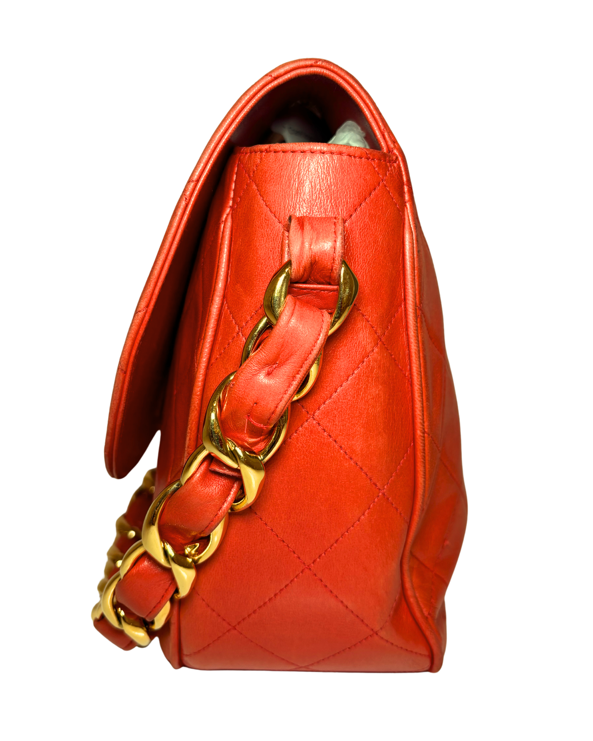 A bright orange-red quilted leather shoulder bag with a gold chain strap, shown from a side profile view against a white background.